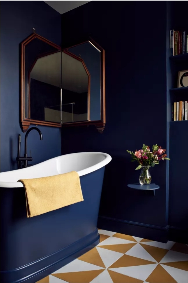 Loft bathroom design with navy-blue walls and dark bathtub